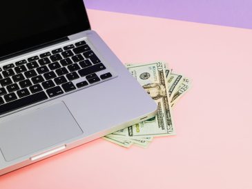 Close-up of a laptop with US dollar bills on a pastel background, symbolizing finance. — Comment Maximiser Votre Exp&eacute;r