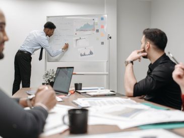 Colleagues in a business meeting discussing data and strategies at the office. — Risk Management Indicator MT4 Solutions for