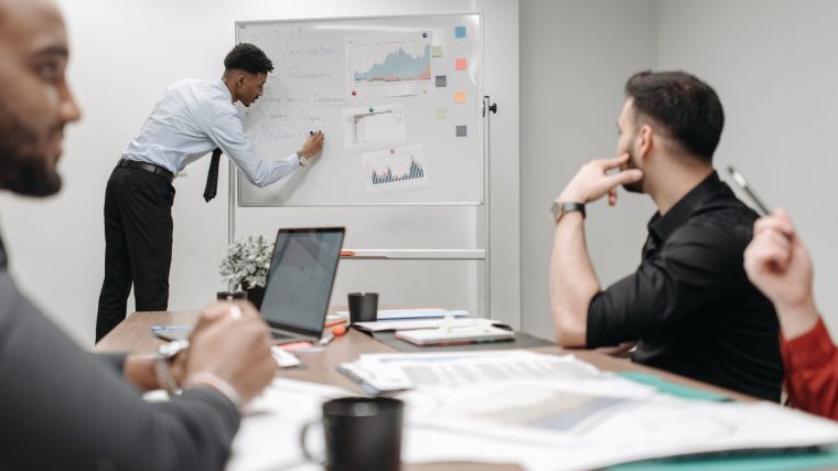 Colleagues in a business meeting discussing data and strategies at the office. — Risk Management Indicator MT4 Solutions for
